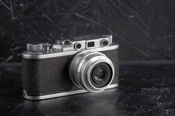 istock Old rangefinder film camera on a black concrete background. 897077666