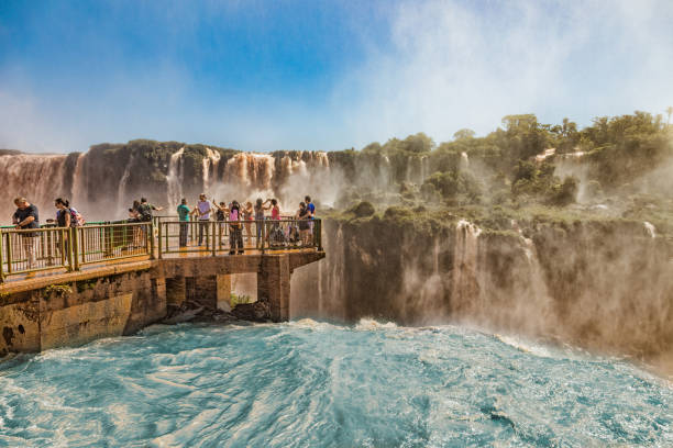 People on a footbridge in the middle of the Iguazu waterfalls on the brazilian side. stock photo