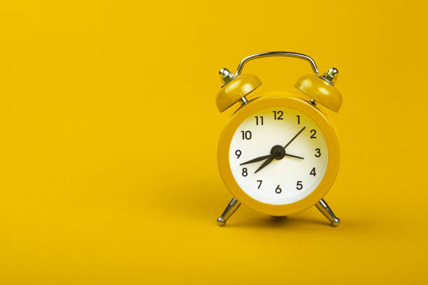 istock Close-Up Of Alarm Clock Over Yellow Background 897098638