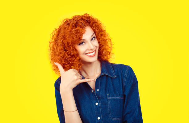 나에 게는 전화를 주세요. 근접 촬영 초상화 빨강 머리 곱슬 머리 여자 흥분 나 노란 배경에 전화 모양 손으로 서명 제스쳐 표시 전화 행복 한 학생. 긍정적인 감정 얼굴 표정 - h shaped 뉴스 사진 이미지