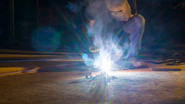 trabajador soldadura metal, foco en línea flash luz de chispa aguda, con poca luz - industrial ship flash fotografías e imágenes de stock