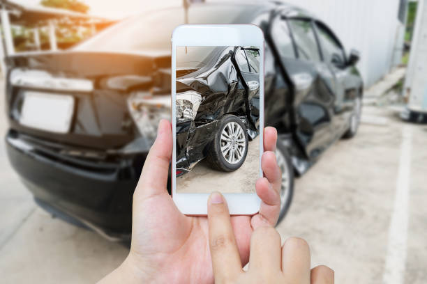 mujer mantenga móvil smartphone fotografiando a accidente de coche - reparar fotos fotografías e imágenes de stock