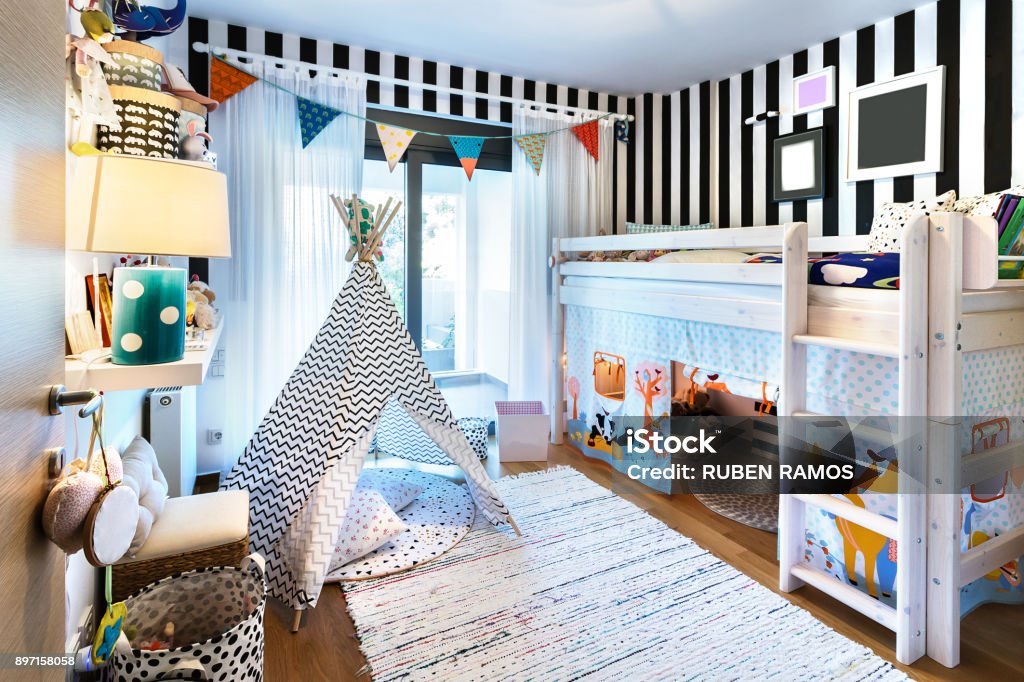 Kid bedroom with teepee and bunk bed. Kids bedroom  with bunk wooden bed, teepee, stands, carpet frames and toys. Child Stock Photo