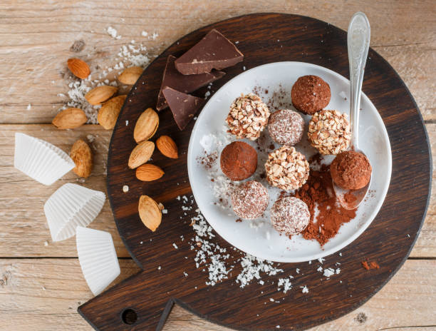 istock Prepare assorted dark chocolate truffles with cocoa powder, coconut and chopped almonds closeup. Homemade candy. Selective focus 897158646