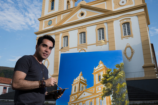 Portrait of an artist painter and his artwork on the actual site. Valença, Rio de Janeiro State, Brazil.