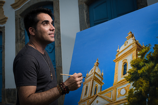 Portrait of an artist painter and his artwork on the actual site. Valença, Rio de Janeiro State, Brazil.