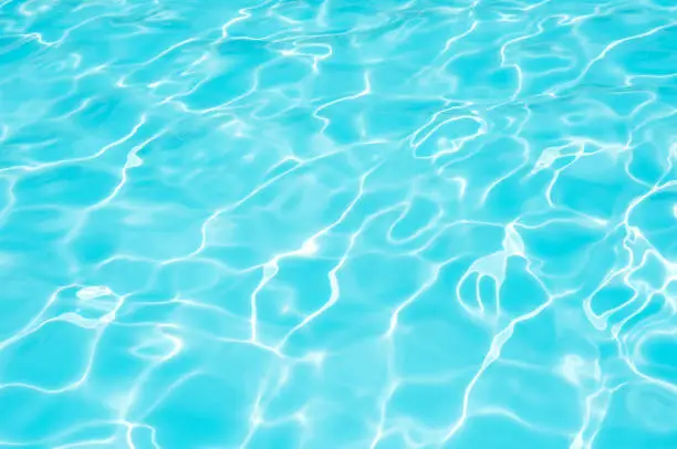 Blue and bright water surface with sunreflection in swimming pool