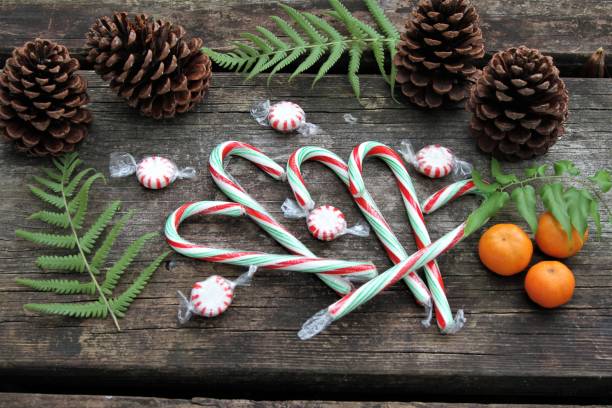 istock Christmas Home Decor: Christmas background with fruit, candy canes, pine cones on weathered wood burning 897186264