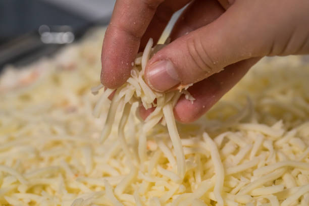 Sprinkling Cheese Someone sprinkling mozzarella cheese on some food shredded mozzarella stock pictures, royalty-free photos & images