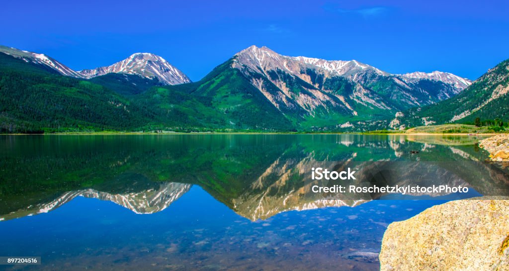 Mirrored Reflection of Rocky Mountains Highest Peak in Colorado Mount Elbert and Twin Peaks Mirrored Reflection of Rocky Mountains Highest Peak in Colorado Mount Elbert and Twin Peaks on a gorgeous summer day in morning sunshine with a blue sky at Twin Lakes , Colorado my favorite place to spend outdoors in nature landscape Mountain scene. Colorado Springs Stock Photo
