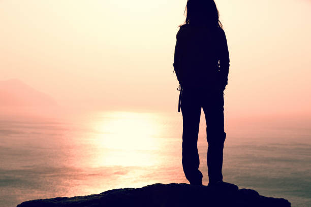 istock female hiker stand on the cliff edge at sunrise seaside 897209772