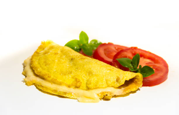 istock omelette made with beaten eggs stuffed with onion cheese and tomatoes on white background with sliced tomatoes and basil 897210376