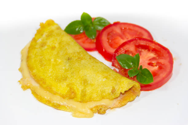 istock omelette made with beaten eggs stuffed with onion cheese and tomatoes on white background with sliced tomatoes and basil 897210390