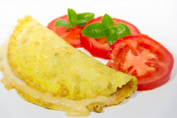 istock omelette made with beaten eggs stuffed with onion cheese and tomatoes on white background with sliced tomatoes and basil 897212434