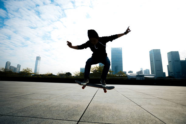 istock female skateboarder jumping with skateboard on city 897212582