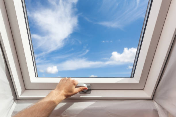 Man close new skylight (mansard window) in an attic room against blue sky Man close new skylight (mansard window) in an attic room against blue sky skylight stock pictures, royalty-free photos & images