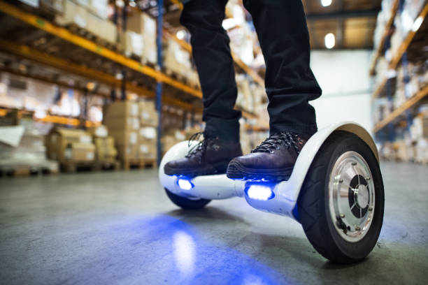 Male warehouse worker on hoverboard. Unrecognizable man warehouse worker on a hoverboard. hoverboard stock pictures, royalty-free photos & images
