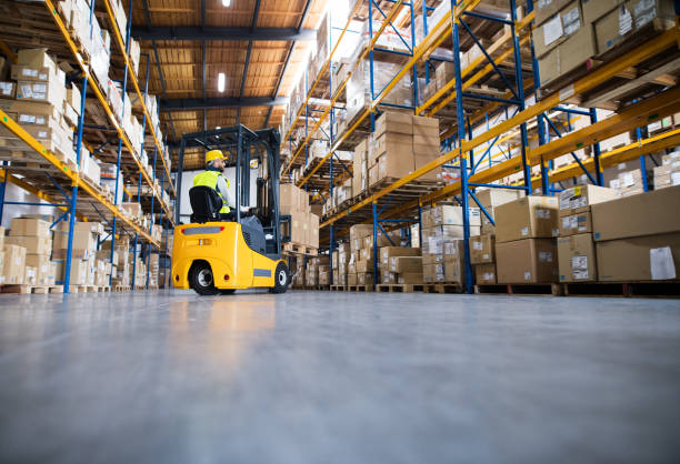 Warehouse man worker with forklift. Young male worker lowering a pallet with boxes. Forklift driver working in a warehouse. distribution warehouse photos stock pictures, royalty-free photos & images