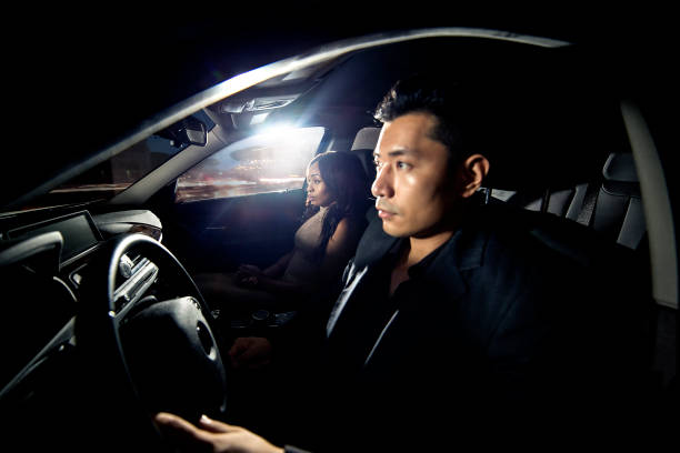 Interracial Dating Couple Driving In a Car Asian man driving with a black african female date in a car. They look like they are heading to a nightclub for clubbing nightlife. The image depicts interracial relationships and lifestyle. couple driving at night stock pictures, royalty-free photos & images