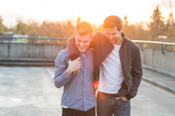 giovane coppia gay maschile cammina fuori mentre il sole tramonta - alternative health care foto e immagini stock