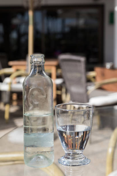 istock Cold fresh water in glass bottle with glass on a cafe table, vertical image 897302764