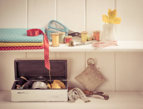 Interior design for seamstress. Set of reel of thread, centimeter, fabric, thimble and scissors, seam ripper, toothed wheel, needle and pins for sewing and needlework on the wooden shelf