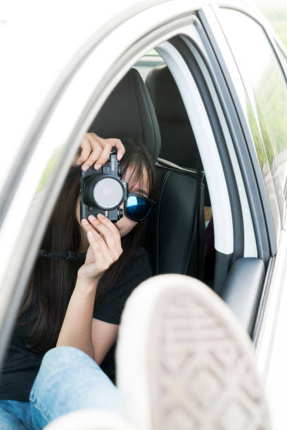 istock cheerful woman in car taking photos with camera 897312112