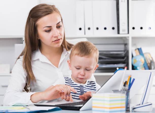istock Woman with child is working behind laptop 897318524