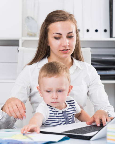 istock Girl with kid is working behind laptop 897318544