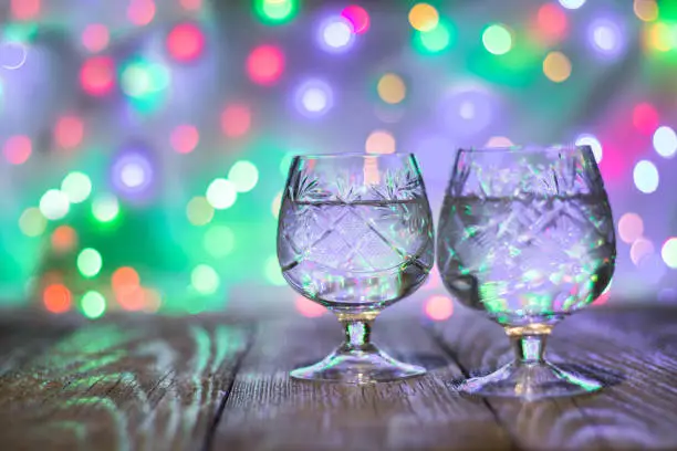 Photo of two glasses of champagne against bokeh lights background