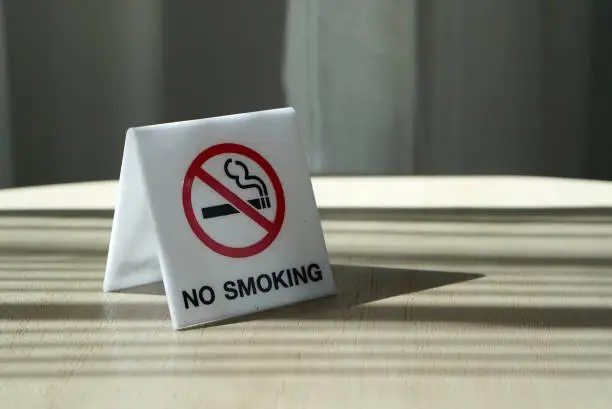 Photo of generic no smoking signage on white acrylic on timber table