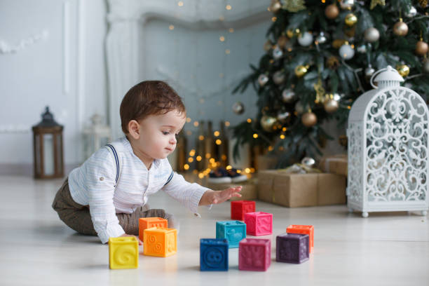 istock Cute little boy playing near the Christmas tree with colored cubes 897319454