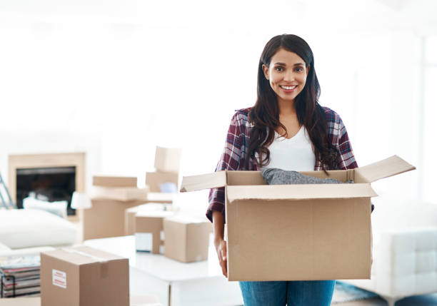 Moving on to bigger and better things Cropped shot of a beautiful young woman carrying a cardboard box in her new house home ownership women stock pictures, royalty-free photos & images