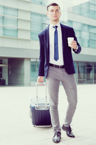 istock Man in suit with suitcase is drinking coffee 897328976