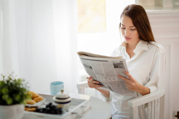 istock Young beautiful woman reading magazine at table 897344680