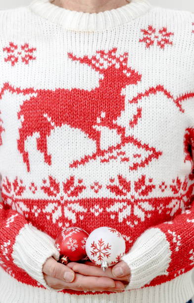 istock Man in winter sweater holding Christmas balls in hands. Close up, copy space, vertical composition. 897350530