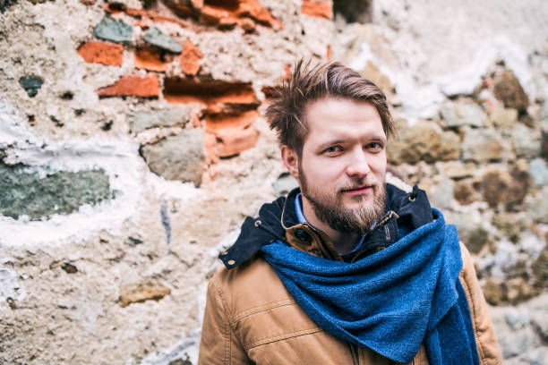 istock A young hipster man standing against an old brick wall. 897353104