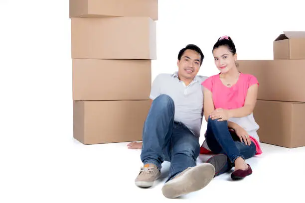 Image of young couple is relaxing together during moving to his new home and sitting near stacks of cardboard