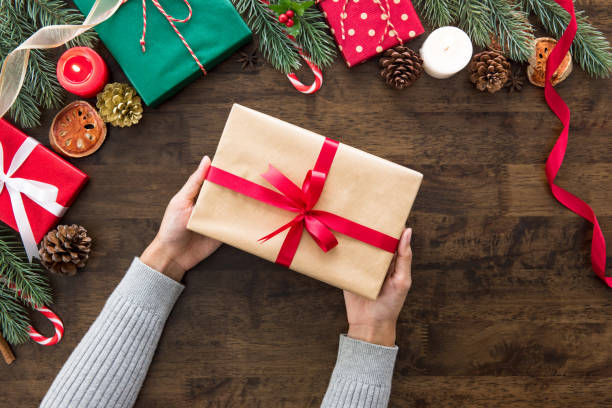 istock Woman hands showing Christmas gift on wood table 897356800