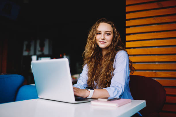 istock Half length portrait of gorgeous blonde woman looking at camera while doing remotely work on laptop connected to wireless internet.Beautiful creative female freelancer using modern technology indoors 897366948