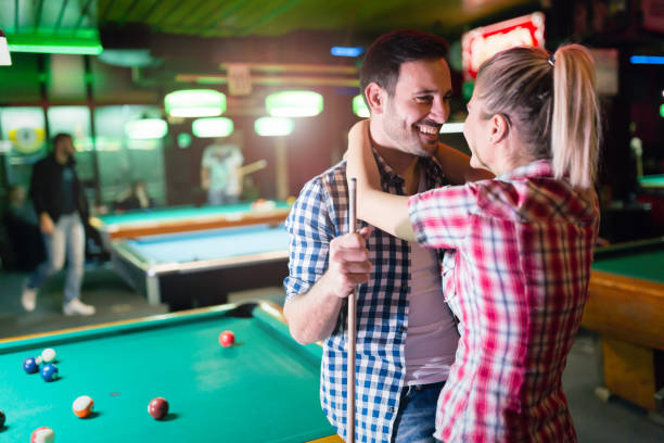 istock Young couple playing together pool in bar 897371390