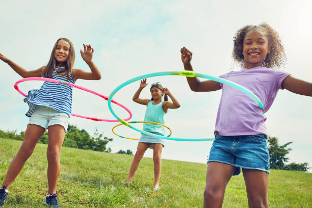 It’s hard not to be happy when you’re hula hooping Shot of a group of young girls playing with hula hoops in the park only girls stock pictures, royalty-free photos & images