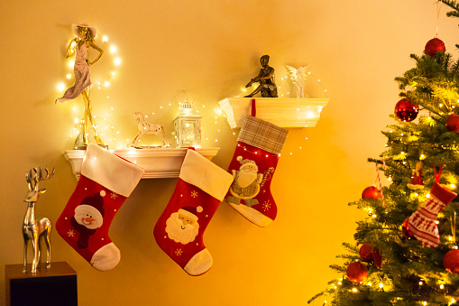 Well decorated Christmas tree with three stockings hanging near it, in a living room.