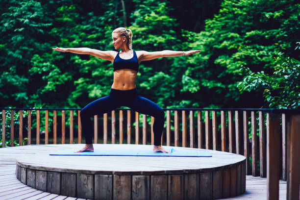 istock Sportive young woman pulling arms out to side while making squat during training on caremat outdoors on green promotional background.Fitness girl making stretching exercises during pilates 897394990