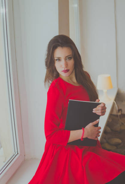 istock at the window with a book a beautiful girl 897399274