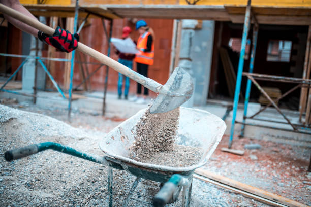 Shovelling on construction site Manual worker is shovelling on construction site. Two architects are in the back and are looking at blueprints. building sand stock pictures, royalty-free photos & images