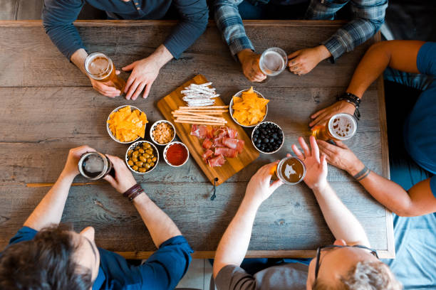 top view of friends sitting over beer at the table in pub - rustic beer brewery indoors imagens e fotografias de stock