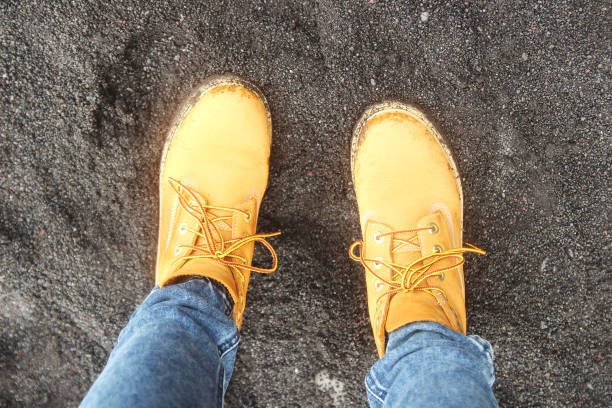 istock Yellow hiking boots on black sand 897450888