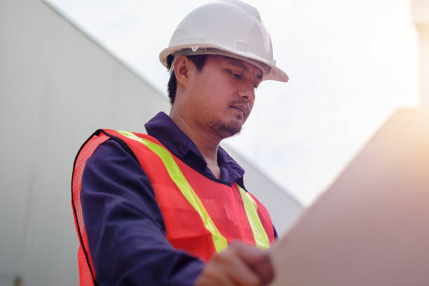 istock Asian engineer in safety uniform holding project plan 897461818