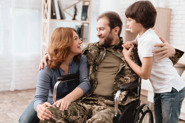 the veteran in a wheelchair came back from the army. a man in uniform in a wheelchair with his family. - physical impairment wheelchair disabled accessibility imagens e fotografias de stock